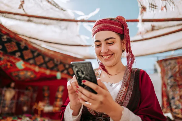 A woman smiling by bright slot machines showing lucky symbols, showcasing the exciting slot offerings at TALABAT.